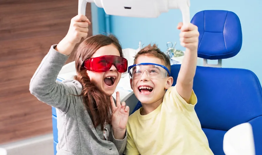 Two happy children wearing safety glasses in the dental chair